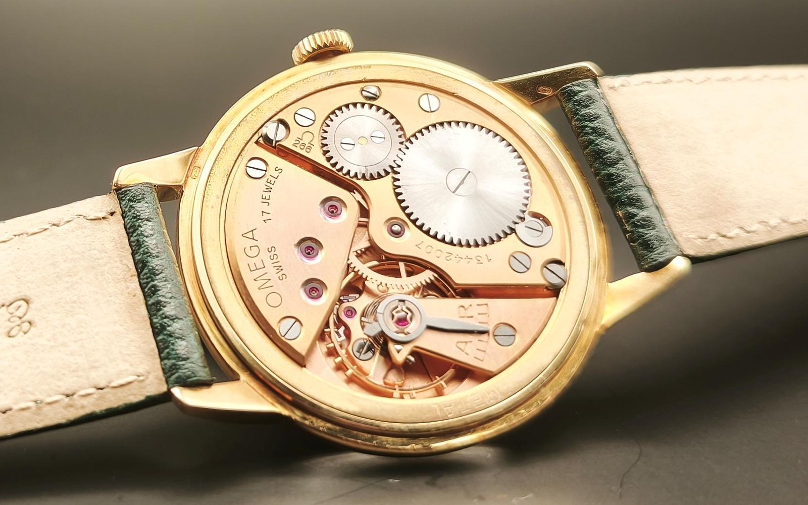 Vintage Omega Caliber 266 mechanical watch movement showing brass mechanism, intricate gears, balance wheel, handcrafted components with 17 jewels, and Incabloc shock protection from 1952