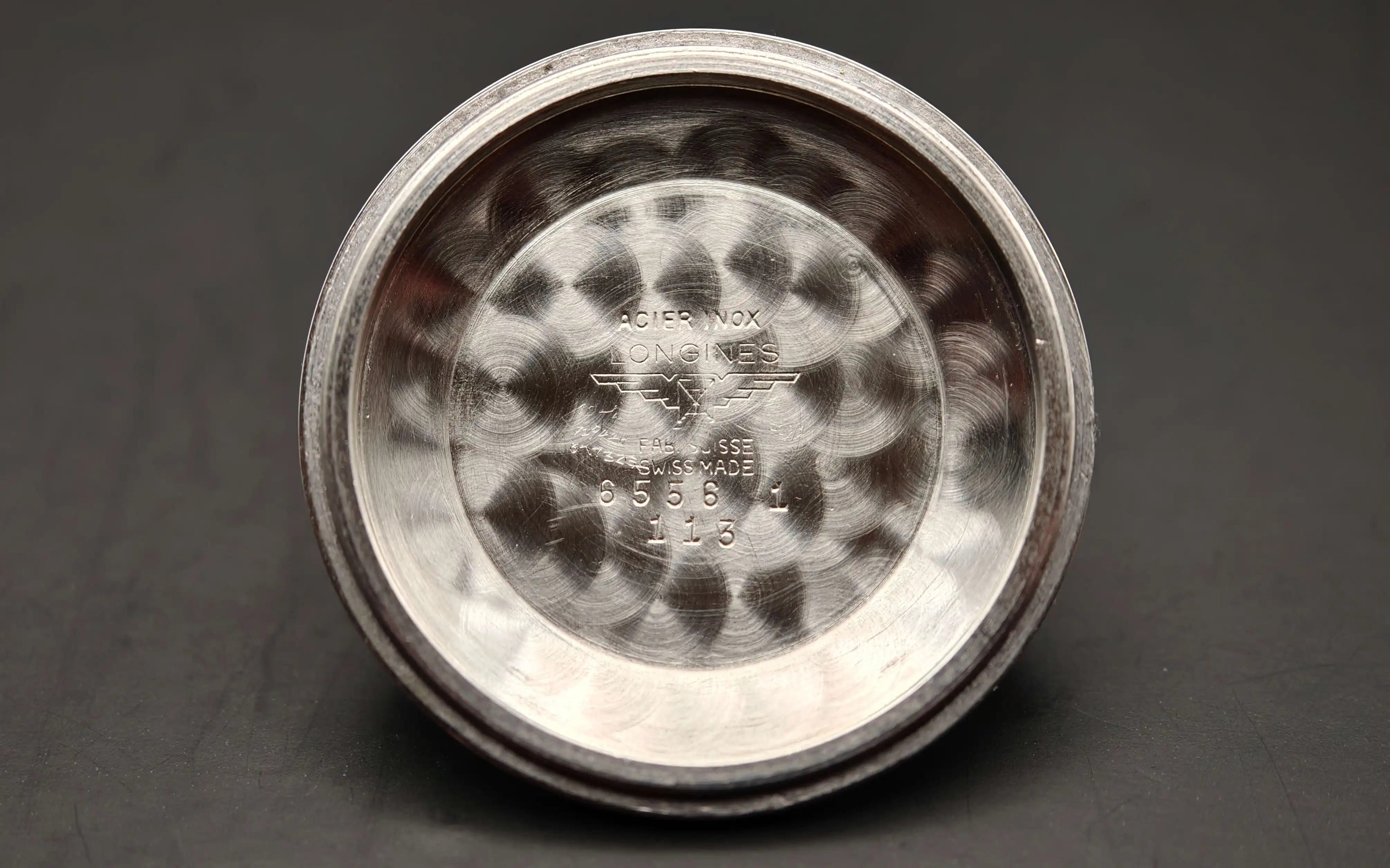 Vintage Longines stainless steel watch case back from 1954 showing hallmarks, reference number 6556, engraved details, steel patina, and vintage watch authentication marks from private watch collection.
